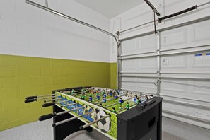 A foosball table in a room with a garage door and a green wall.