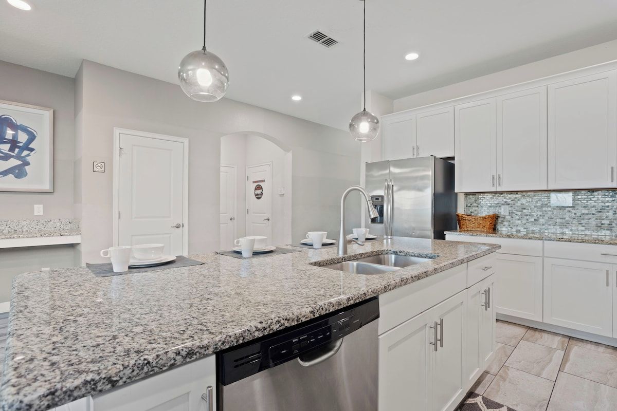 A modern kitchen with granite countertops, stainless steel appliances, and white cabinetry.