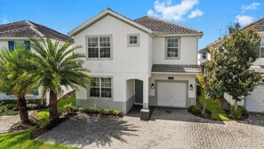 A two-story residential building with a garage, a driveway, and a well-maintained lawn. - Kissimmee Bliss: 6BR Pool Home w Game Room (Kissimmee)