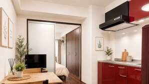 A modern kitchen with a dining area, wooden flooring, and red cabinets.