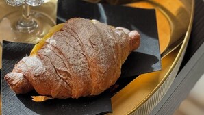 Un vassoio con un cornetto, un dolce al cioccolato e una tazza decorata con un motivo a cioccolato.