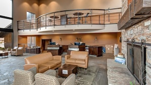 A spacious lobby with leather sofas, a fireplace, a reception desk, and a mezzanine with a balcony. - Ground Floor, In-Home Laundry, Ski Bus | Sleeps 3 | Moose Mgt 717 (Park City)