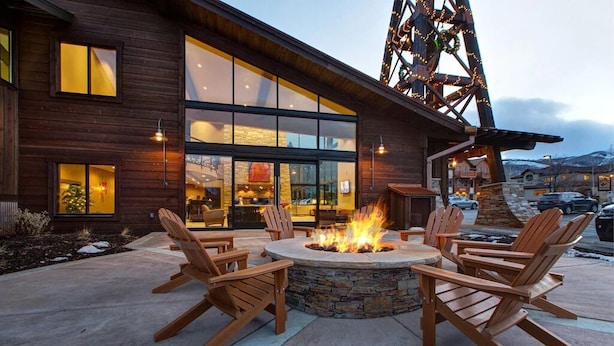 A wooden building with large windows and a fire pit with chairs. - Ground Floor, In-Home Laundry, Ski Bus | Sleeps 3 | Moose Mgt 717 (Park City)