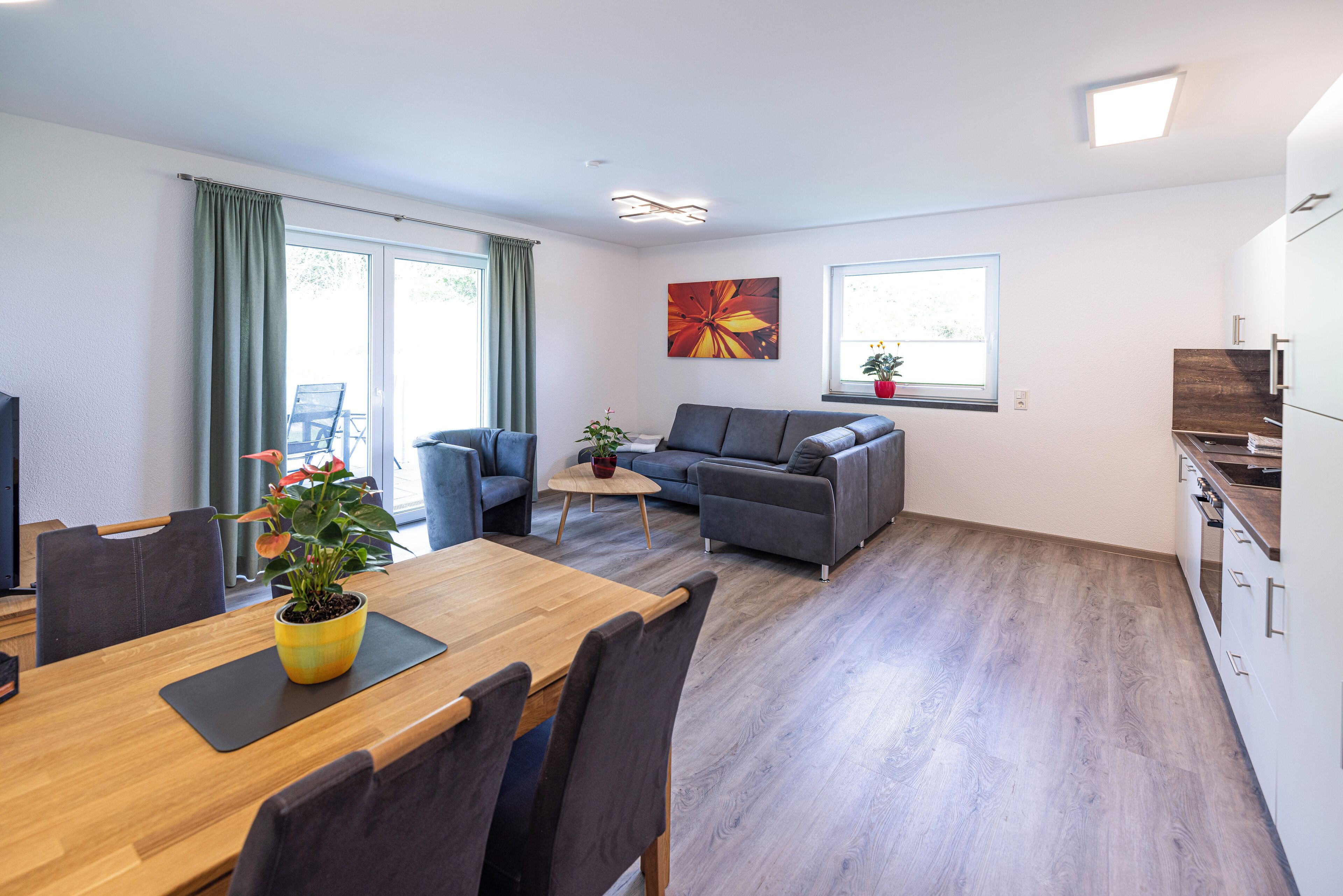 Una sala de estar moderna con un sofá, una mesa de comedor con sillas y una zona de cocina.