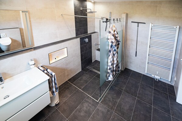 Une salle de bain moderne avec une douche à parois de verre, un lavabo blanc et un porte-serviettes.