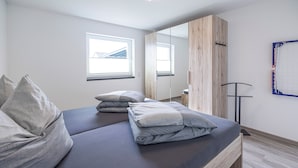 A modern bedroom with a bed, pillows, a wooden wardrobe, and a window. - Vacation residence Hunsrück Hochwald (Mörschied)