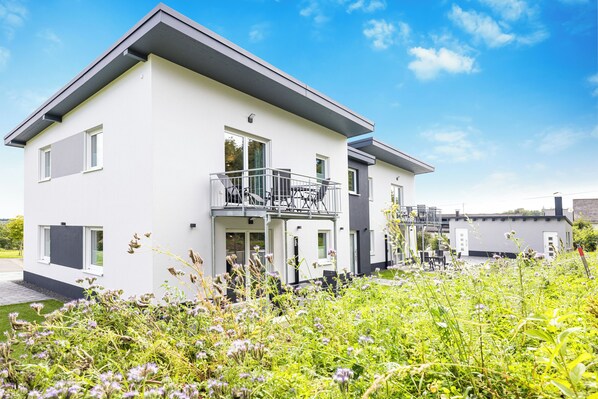 A modern two-story house with a balcony, surrounded by lush greenery. - Hunsrück Hochwald Vacation Resort (Mörschied)