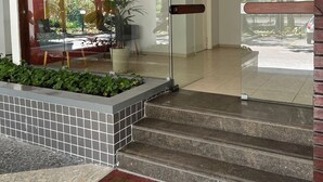 Un vestíbul d'hotel modern amb entrada de vidre, una recepció i una escala que mena a la planta superior.