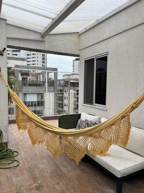 Ein Hängesessel auf einem Balkon mit Blick auf umliegende Gebäude.