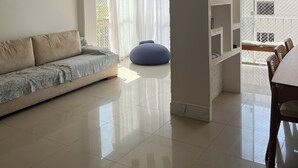 Un ampli saló amb sofà, una butaca de plàstic i zona de menjador amb taula i cadires.