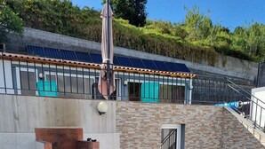An outdoor patio with a brick fireplace, a round table, and chairs. - Casa Agapanthe House  (Estreito da Calheta)