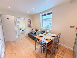Un appartement moderne comprenant un coin repas, un canapé, une fenêtre avec vue et une porte donnant sur une autre pièce.