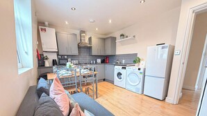 A compact kitchen with modern appliances, a dining area with a table and chairs, and a living space with a sofa.