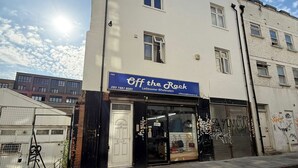 A building with a sign 'Off the Rack Ladieswear Wholesalers' and a closed shop entrance.