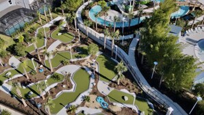 An aerial view of a resort with multiple swimming pools, landscaped areas, and palm trees.