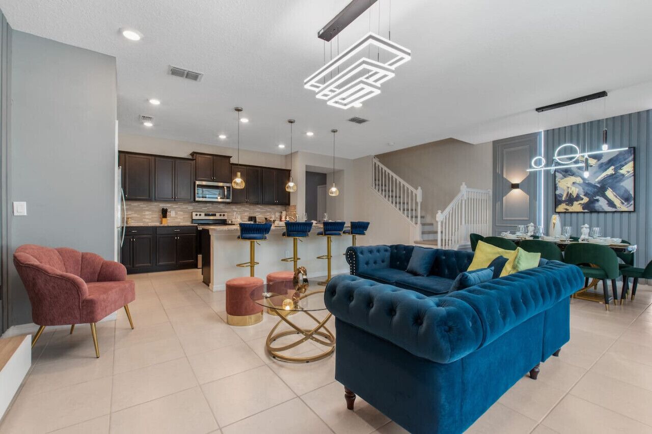A modern living room with a blue sofa, a red armchair, and a glass coffee table.