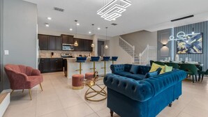 Un salon moderne avec un canapé bleu, un fauteuil rouge et une table basse en verre.
