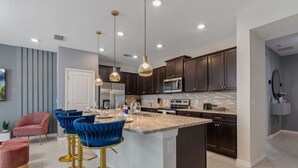 Une cuisine moderne avec des meubles de couleur sombre, un grand îlot central et des tabourets de bar.