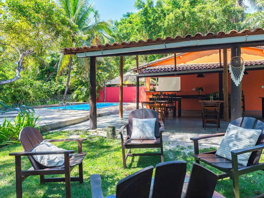 Uma área de estar coberta ao ar livre, com cadeiras e piscina.