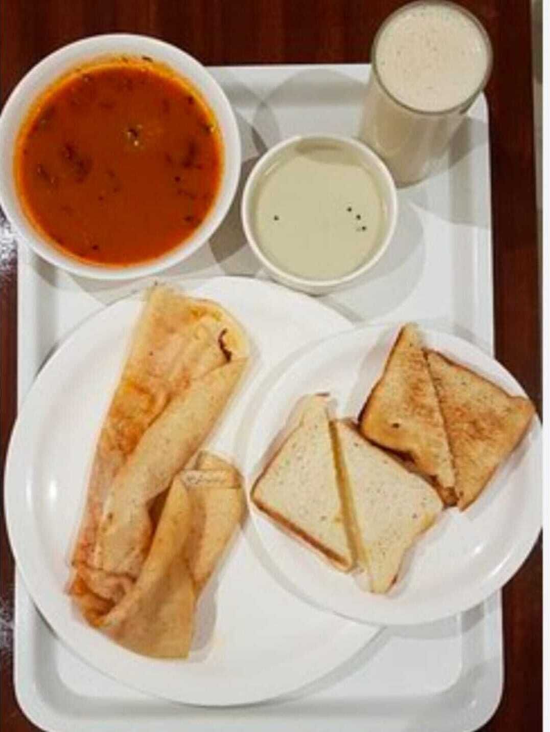 A tray with a bowl of soup, a glass of milk, and two plates of sandwiches.