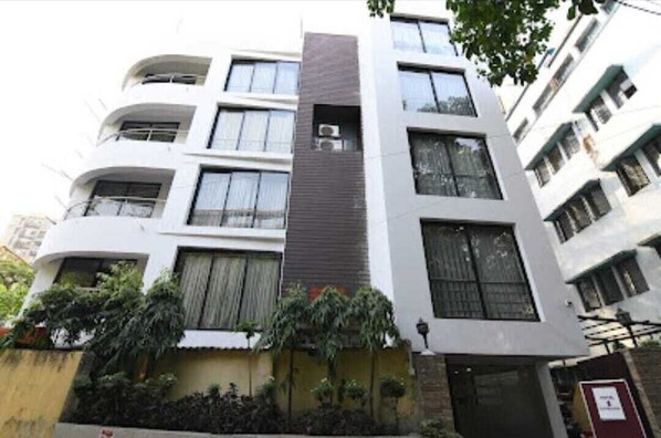 A multi-story building with balconies, large windows, and a central air conditioning unit.