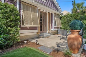 Une maison avec un patio, un grand jardinière et une pelouse.