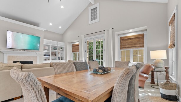 A spacious living room with a wooden dining table, comfortable seating, a flat-screen TV, and a fireplace. - Sea La Vie 3 Bedroom Home (Miramar Beach)