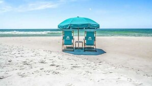 A beach with two beach chairs under a green umbrella. - Sea La Vie 3 Bedroom Home (Miramar Beach)