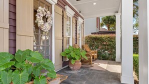 A covered porch with large potted plants, wicker chairs, and a decorative wreath. - Sea La Vie 3 Bedroom Home (Miramar Beach)