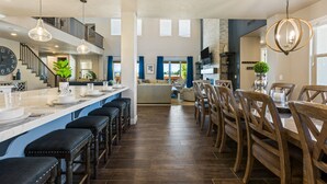 Una cocina amplia con una isla grande, taburetes de bar y un comedor con sillas de madera.