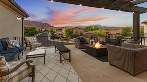 Un patio al aire libre con un brasero, asientos y vista a un área residencial.