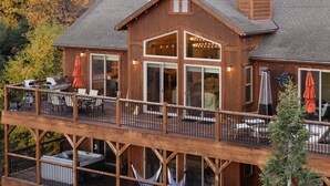 Eine zweistöckige Holzhütte mit Balkon, Sitzgelegenheit im Freien und Kamin.