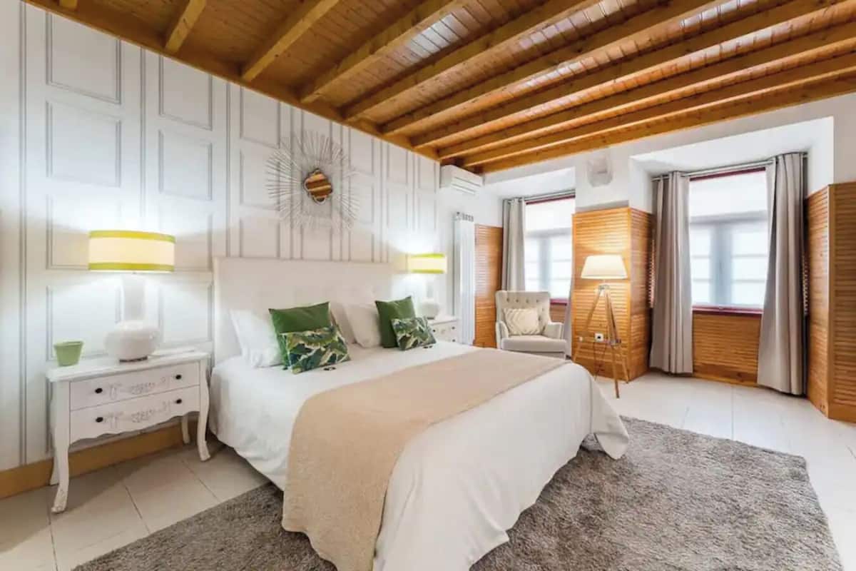 A bedroom with a large bed, a nightstand, a chair, and a lamp.