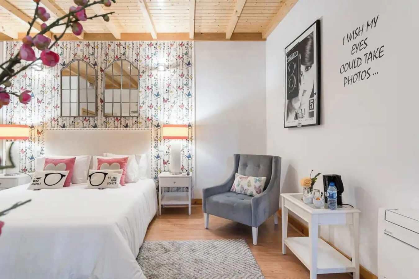Een slaapkamer met een bed, een stoel, een nachtkastje, een lamp en een muur met een poster.