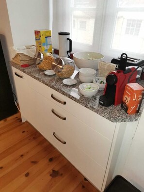 A kitchen with a granite countertop, a coffee machine, a kettle, and various kitchen items.