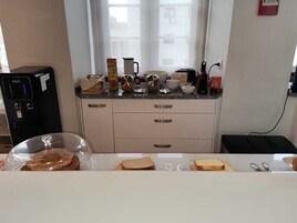 Una cocina con una cafetera, un hervidor y varios utensilios de cocina sobre la encimera.
