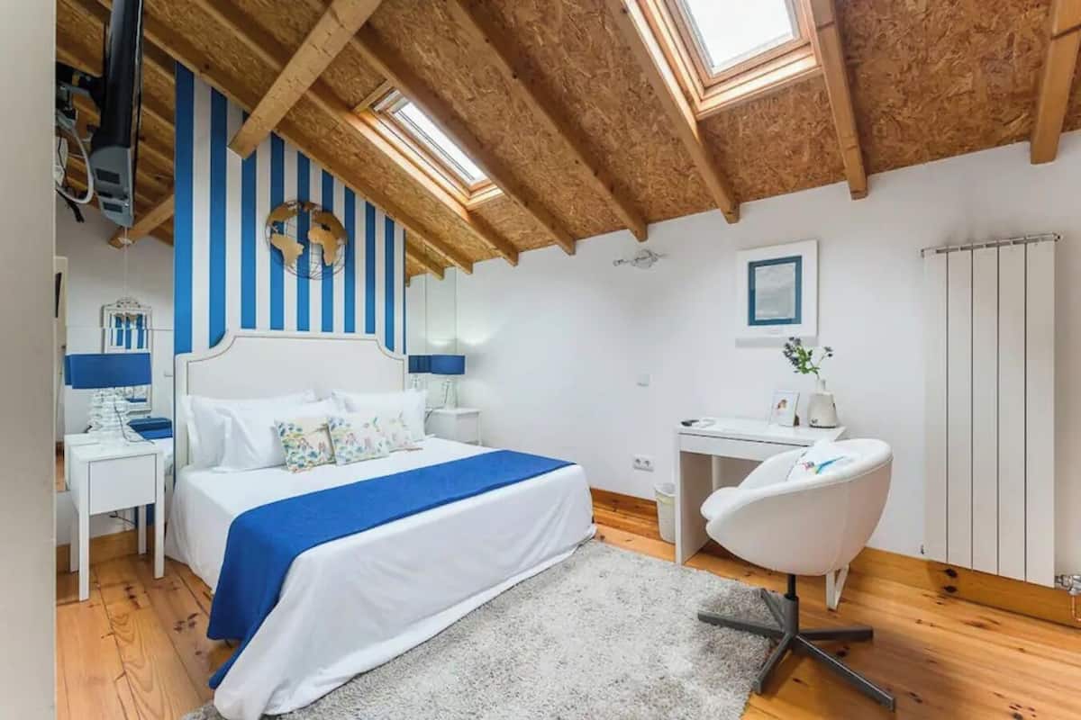 A bedroom with a bed, a desk, a chair, and a radiator.