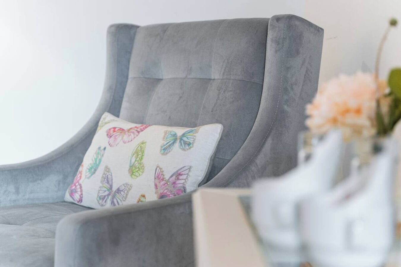 Un sillón gris con un cojín estampado con motivos de mariposas.