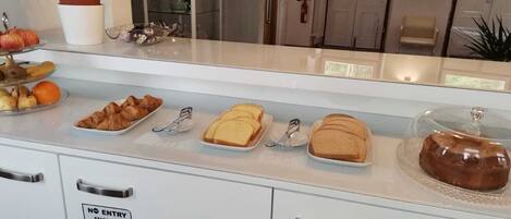 A breakfast buffet with croissants, bread, and pastries.