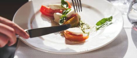 A plate of food with a fork and knife on a table with a placemat labeled "AZZURRO CLUB VACANZE".