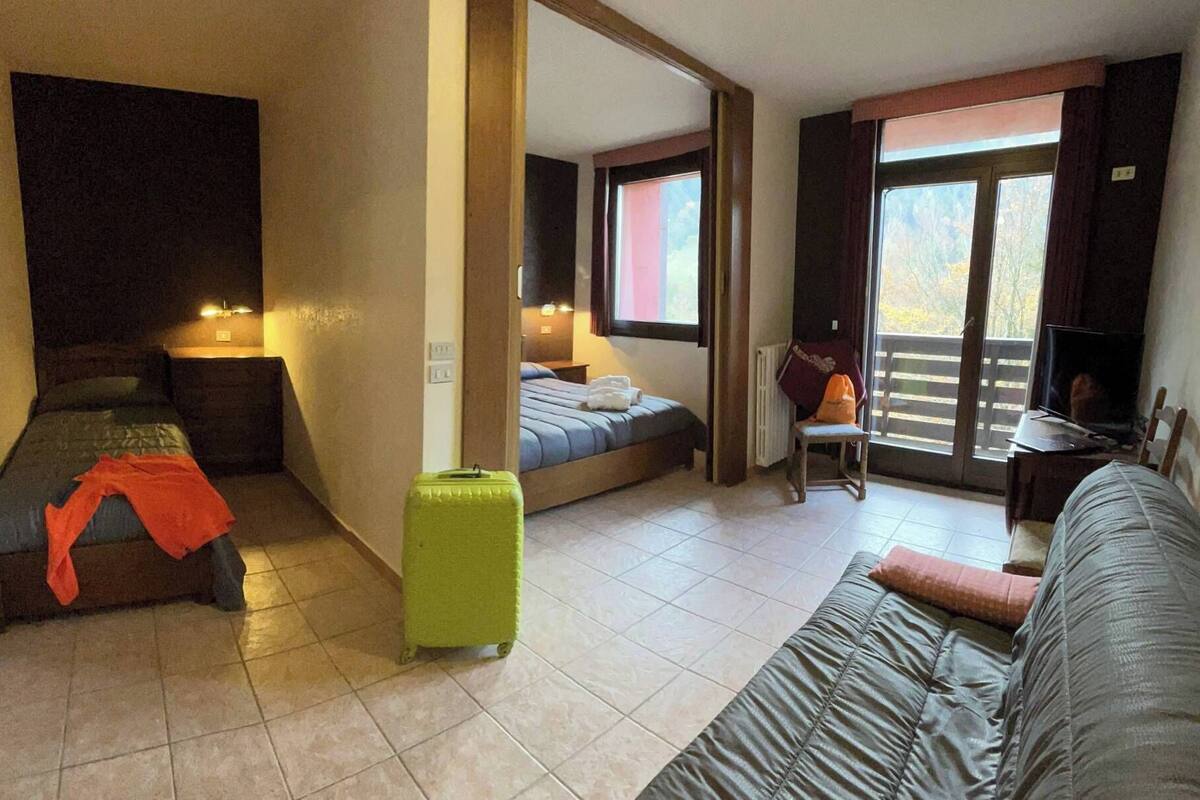 Une chambre d’hôtel avec un lit, un canapé, une chaise, une petite table et une valise.