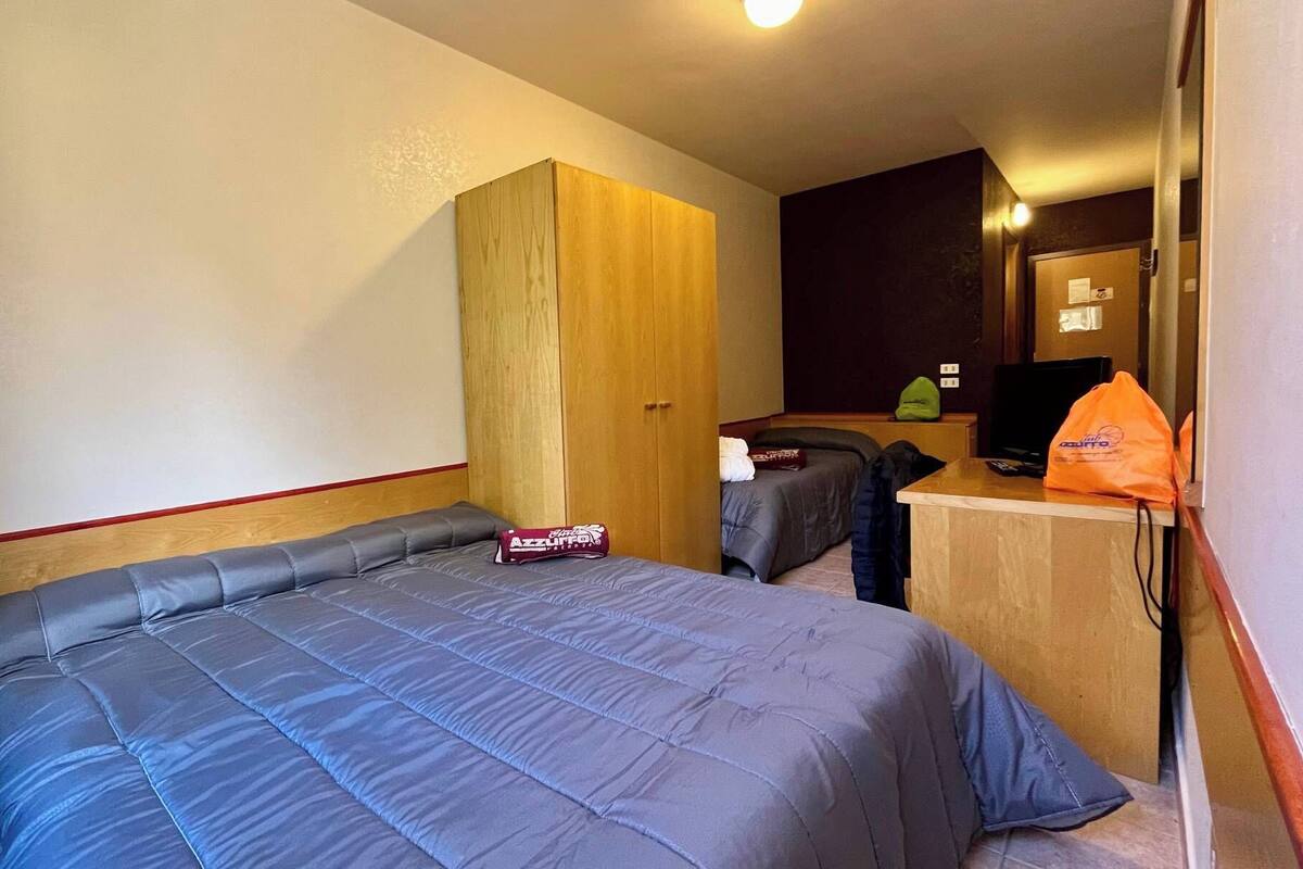 Une chambre d’hôtel avec un grand lit, une armoire en bois, un bureau avec un ordinateur et une télévision.