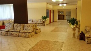 A spacious lobby with a sofa area, a tiled floor, and potted plants. - Forte Family Village (Chiusaforte)