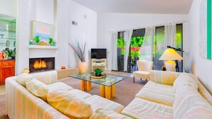 A modern living room with a fireplace, sofa, TV, and a glass coffee table. - 25% Off, 30+ Night Stay! Family Getaway W/Pool/Spa (Palm Springs)