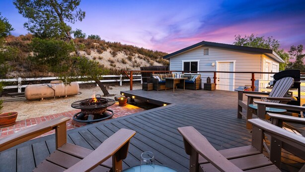 A deck with outdoor furniture, a fire pit, and a building in the background. - 30+ Night Stay! Beautiful Property - Spa, Views, LRG Patio! (Temecula)