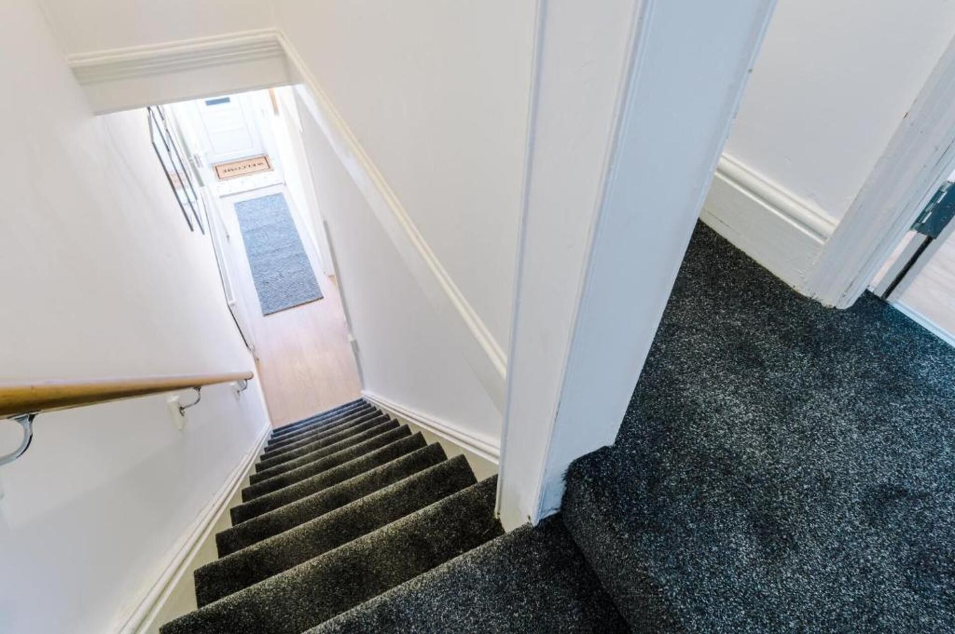 A staircase with a carpeted landing and a wooden handrail.