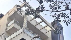 A modern multi-story building with balconies, a car parked in front, and a street lamp. - Green Valley Suites (Bengaluru)