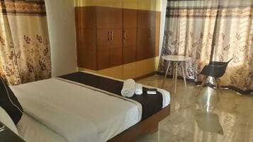 Une chambre d’hôtel avec un lit, une armoire, une petite table et une chaise.