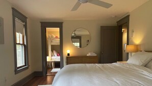 A bedroom with a large bed, a ceiling fan, a dresser, a mirror, and a walk-in closet. - Inviting, Cozy Catskills Home - Primed for Fall! (Shandaken)