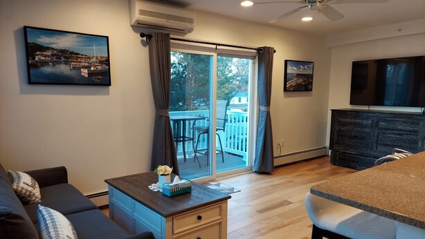 A living room with a sofa, a coffee table, a TV, and a sliding glass door leading to a balcony.